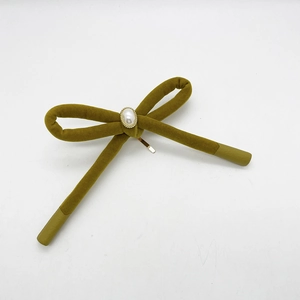 Detail of olive green velvet bow hair clip with white pearl and gold metal clasp