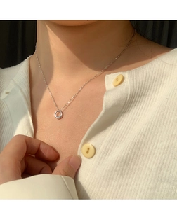Close-up of minimalist silver circle pendant necklace on a woman's collarbone
