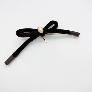 Detail of dark brown velvet bow hair clip with gold hardware and center pearl decor