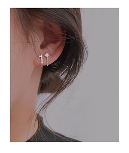 Macro detail of asymmetric silver ear cuff with sparkling zircon stones on human ear