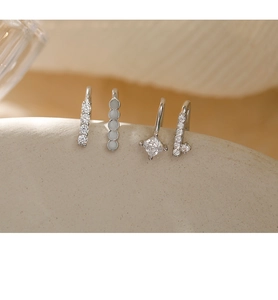 Detailed macro view of four minimalist silver ear cuffs with cubic zirconia stones