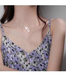 Detail of silver double butterfly necklace on model featuring white shell pendant