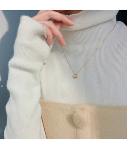 Minimalist gold circle pendant necklace shown on a white ribbed knit sweater for styling