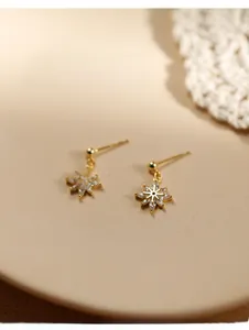 Macro d'une boucle d'oreille flocon dorée sertie de zircons marquise étincelants