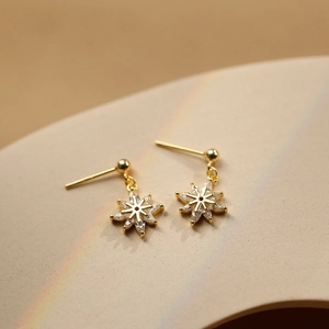 Élégantes boucles d'oreilles flocon de neige dorées avec zircones en vue macro