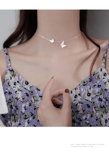 Detail of minimalist silver butterfly necklace with matte finish on a female model