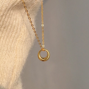 Minimalist gold geometric circular pendant necklace with fine chain on knit fabric