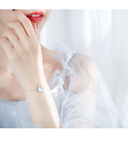 Détail d'un bracelet gourmette en argent avec un pendentif chat en pierre de lune