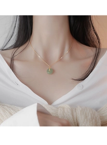 Gros plan détaillé du pendentif en jade pingan-kou sur une fine chaîne dorée en argent S925