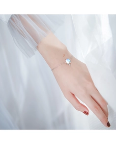 Bracelet licorne en argent délicat avec pierre de lune irisée au poignet féminin