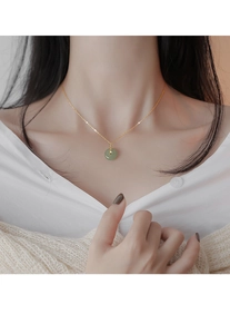 Gros plan d'un modèle portant une chaîne en or avec pendentif donut en jade vert