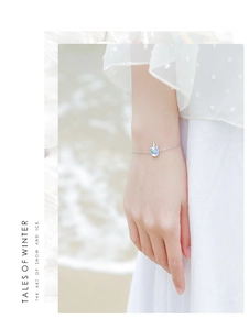 Détail d'un bracelet licorne en argent avec pierre de lune au poignet sur fond de mer d'hiver