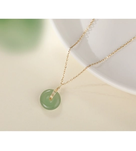 Gros plan d'un pendentif en jade vert vintage avec une chaîne dorée pour femme
