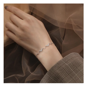Détail du bracelet argenté à ondes en V avec trois breloques en forme de cœur