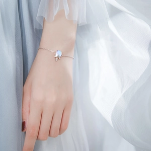 Bracelet licorne élégant avec pierre précieuse irisée et glands au poignet féminin