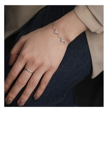 Détail d'un bracelet en argent forme vague en V orné de zircons porté au poignet