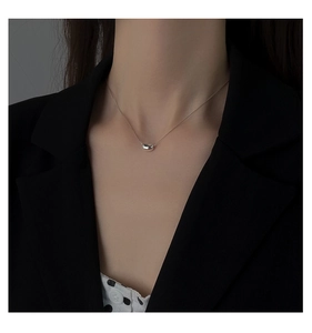 Close-up of a silver bean pendant necklace on a model wearing a professional suit