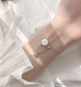 Macro detail of silver daisy bracelet featuring white petal charm and adjustable clasp