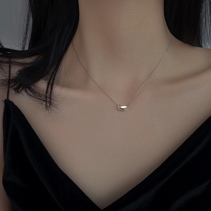 Minimalist silver bean pendant necklace on a sleek chain worn by a female model