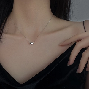 Minimalist silver red bean pendant necklace on a delicate chain worn by a female model