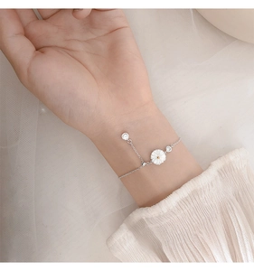 Detailed close-up of a silver daisy bracelet with shell petals and sparkling zircons