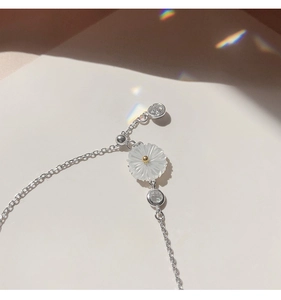 Close-up of silver daisy bracelet with white shell petals and sparkling zircon detail