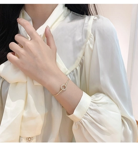 Detail van een gouden verstelbare slangenarmband met een fonkelende pavé gezette ring