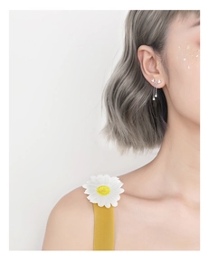 Gros plan de boucles d'oreilles papillon argentées avec pompons portées par un mannequin