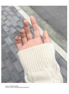 Close-up of minimalist double-layer silver ring worn with a textured knit sweater