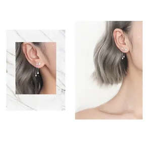 Détail des boucles d'oreilles papillon argentées avec de longues chaînes sur marbre