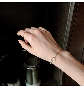 Detailopname van gouden armband met micro-pave kristallen en witte parelring om hand