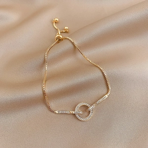 Verstelbare gouden armband met zirkonia ring en slangenketting op zijden stof