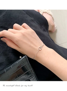 Nahaufnahme eines silbernen Doppelarmbands mit einem glitzernden Zirkonia-Ring-Anhänger