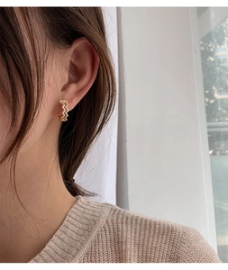 Close-up model shot of wavy gold hoop earrings with sparkling diamonds in a zigzag design