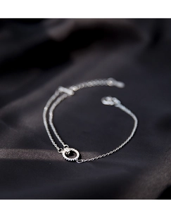 Makroaufnahme eines silbernen Doppelarmbands mit einem kristallbesetzten Kreisanhänger