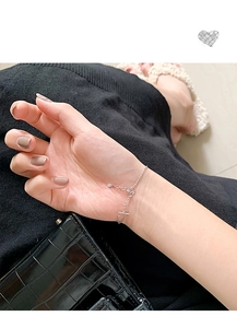 Nahaufnahme eines doppellagigen Silberarmbands am Handgelenk mit schwarzem Strick