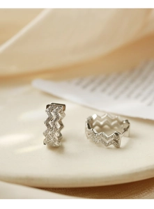 Macro detail of wave-shaped silver hoop earrings with pave set sparkling cubic zirconia stones