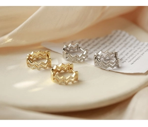 Detailed view of wave-shaped ear hoops in gold and silver with micro-paved zircons