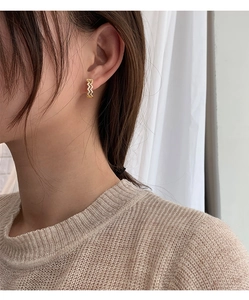 Detailed close-up of wavy gold earrings featuring shimmering cubic zirconia stones