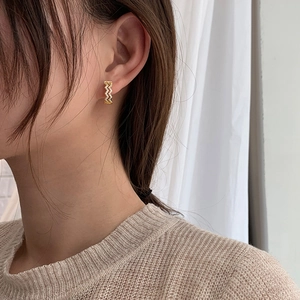 Elegant gold wavy hoop earrings with white zircon crystals on a female model
