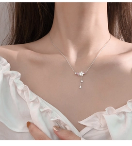 Detail der silbernen Kirschblütenkette mit Muschelblättern am Schlüsselbein der Frau
