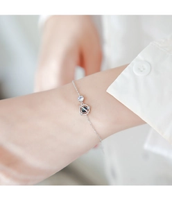 Dettaglio del bracciale minimalista in argento con pianeta e gemma blu sul polso
