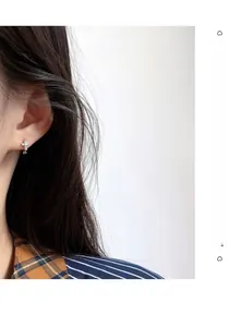 Dettaglio di orecchini a croce minimalisti in argento con scintillanti zirconi cubici