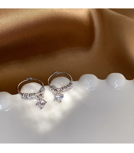 Macro detail of S925 sterling silver hoop earrings with cubic zirconia drops on silk