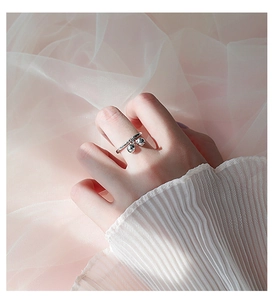Detail of adjustable silver ring featuring double mini bells on model's finger