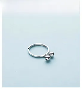 Close-up of S925 sterling silver adjustable ring with small bell charms on light blue background