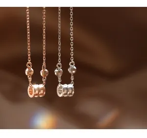 Détails macro des pendentifs cylindriques en argent et or rose sur chaînes croisées