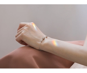 Gros plan d'un bracelet minimaliste en argent S925 avec pendentif cylindre sur le poignet