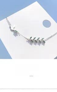 Détail du bracelet en argent avec branche d'olivier en zircon vert et motifs d'hirondelle