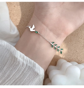 Détail d'un bracelet en argent s925 avec pendentif colombe blanche et branche verte